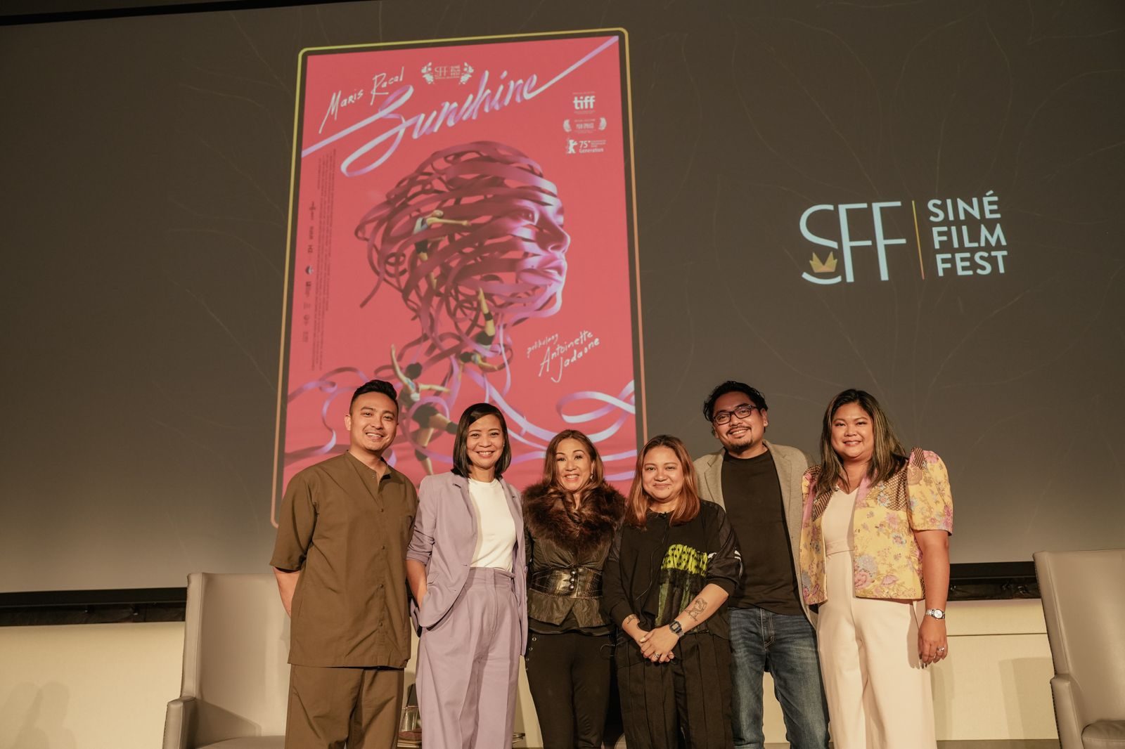 Filmmakers and guests on stage at Siné Film Fest in front of the Sunshine poster